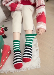 Thick coral fleece Christmas socks featuring festive red and green stripes on cozy carpet