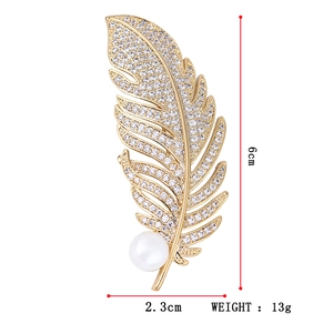 Elegant gold feather brooch with white crystals and a pearl accent, 6cm in height