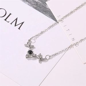Macro detail of silver stag antler necklace with a black projection bead and clear gems