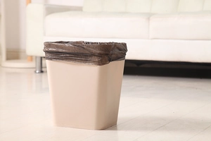 Close-up of durable brown plastic garbage bag fitted inside a beige square waste bin