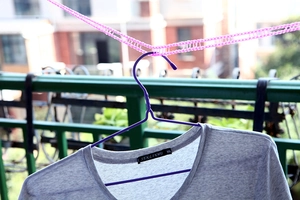 Outdoor windproof pink fence-style clothesline with anti-slip hooks and a purple hanger