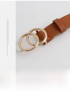 Macro shot of brown leather belt with gold double circle buckle on neutral background