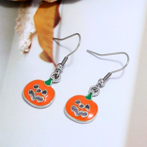 Macro shot of Halloween pumpkin drop earrings with vibrant orange and green enamel finish