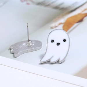 Macro shot of white ghost stud earrings with silver metal backing and black facial detail