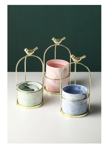 Detail of marble ceramic pots in birdcage metal stands with gold bird top ornament
