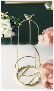 Detail of a golden birdcage metal stand showing top bird motif and sturdy base