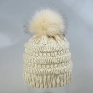 Detailansicht der beigefarbenen Strickmütze mit Rippenstruktur und flauschigem Kunstfellpompon