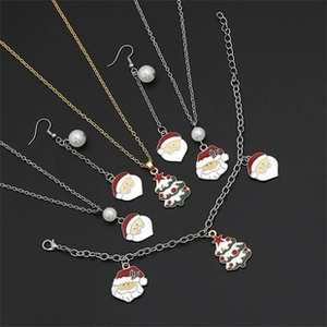 Close-up of enamel Santa Claus and Christmas tree jewelry set with faux pearls
