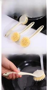 Detail of long-handle wheat straw kitchen brush showing hanging hole and usage on cookware