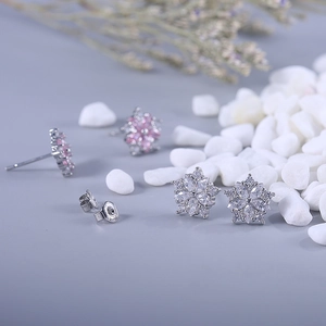 Close-up of sparkling snowflake flower stud earrings with crystals on stone background