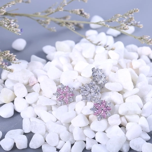 Macro shot of elegant flower stud earrings with shimmering zircons on white stones