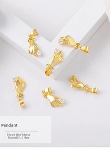 Detail of gold palm pendant with clear zircon inlay on a minimalist white background