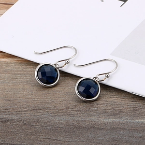 Elegant silver earrings with round blue gemstones on a natural wooden background