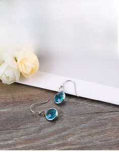 Close-up of titanium drop earrings with faceted blue crystals on a wooden texture
