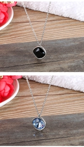 Detailed view of silver necklaces with square black and blue gemstone pendants on wood