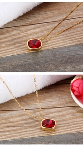 Detail van een gouden ketting met een vierkante rode edelsteen hanger op hout