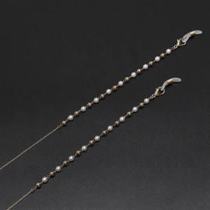 Détail de la chaîne dorée avec perles blanches et connecteurs de lunettes en silicone
