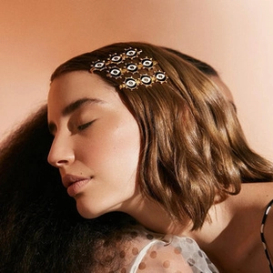 Close-up of a gold metal evil eye hair clip worn by a model for a vintage look