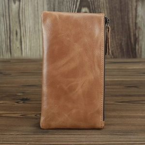 Detailed side view of a brown crazy horse leather long wallet with zipper on wood background