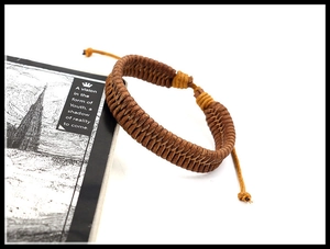 Detail of hand-woven brown leather cord bracelet with adjustable drawstring closure