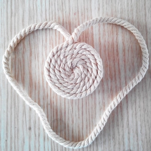 Detail of beige cotton woven heart decor and matching round coaster on wood surface