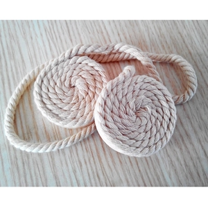 Macro detail of natural beige braided wooden magnetic curtain tiebacks on a wooden surface