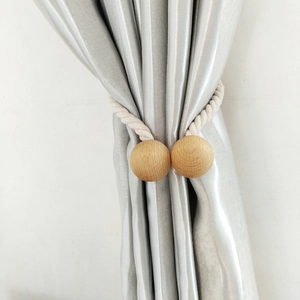 Detail of beige cotton rope curtain tieback with natural wooden bead on white background