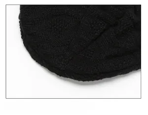 Detailed close-up showing the tight stitching and knit texture on the top of the black beanie
