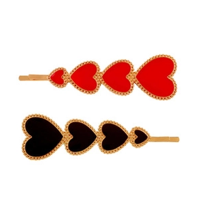 Detail of red and black heart hair clips with golden beaded edges on white background