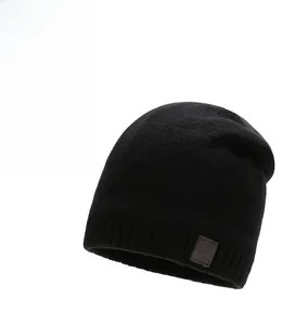 Close-up of thick ribbed knit texture and sport leather patch on a black winter beanie
