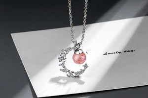 Macro shot of silver moon pendant with strawberry quartz crystal and sparkling zircon details