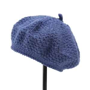 Detail of navy blue hand-knitted beret showing thick wool texture and top knot