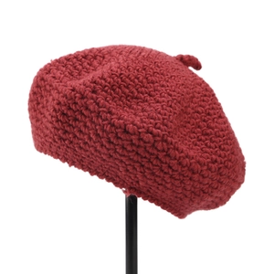 Detailed knit texture and top accent of a dark red wool beret on a white background