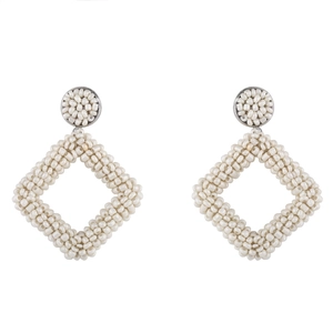 Detail view of handmade white seed bead woven earrings featuring geometric rhombus charms