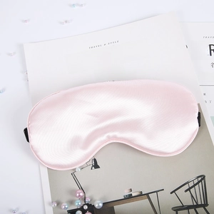 Pink satin silk sleep mask with adjustable strap and decorative pearls on white background