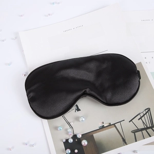 Close-up of black silk sleep mask with satin texture on white magazine background