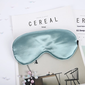 Detail of silk-like blue sleep mask with elastic strap on a magazine with pearls