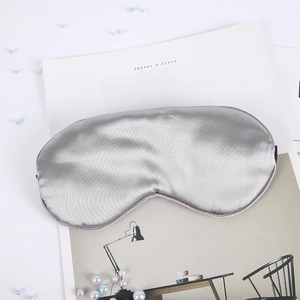 Detailed view of silver silk sleep mask with elastic strap on minimalist aesthetic magazine