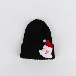 Dettaglio del berretto in maglia nera con toppa di Babbo Natale 3D sul bordo risvoltato
