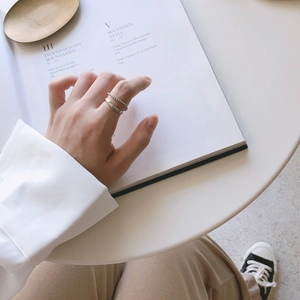 Minimalist silver chain ring and smooth wide band set displayed on a fashion book