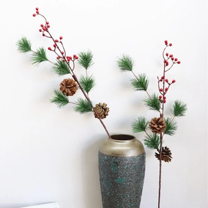 Artificial Christmas pine branch with red berries and pine cone in a ceramic vase