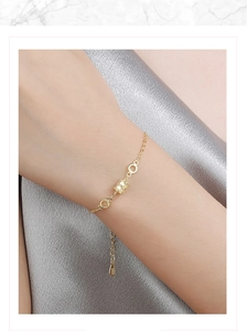 Close-up of golden S925 silver bracelet with checkerboard cylinder pendant on silk