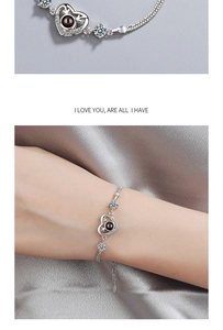 Macro detail of silver heart bracelet with projection stone and I Love You engraving