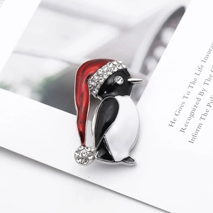 Macro shot of an enamel penguin brooch with a red Christmas hat and rhinestone details