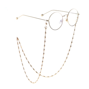 Fashionable golden oval bead eyewear chain with round metallic glasses on white background
