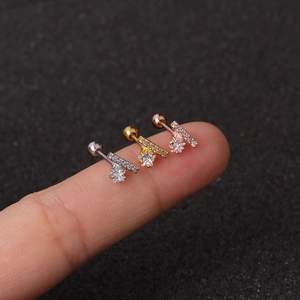 Macro shot of mini flower star cartilage studs in silver, gold, and rose gold on a fingertip