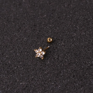 Macro detail of a golden flower cartilage stud with zircon stone and screw back ball