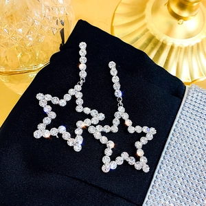 Sparkling silver star drop earrings with pavé crystals on a black velvet background