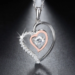 Macro shot of silver and rose gold double heart necklace pendant with sparkling zircon