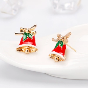 Macro shot of Christmas bell earrings with red enamel and green holly leaves detail